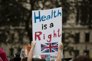 A protestor holds a political banner with health is a human right message