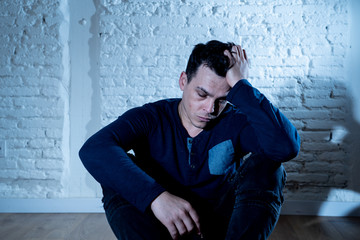 Desperate lonely unhappy caucasian man suffering from depression sitting alone on floor at home