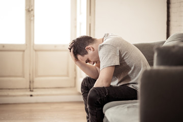 Fototapeta na wymiar Young man suffering from depression lying on sofa alone at home feeling frustrated and hopeless