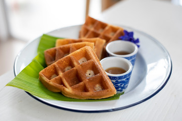 Waffles on banana leaves in a white dish with caramel, Desserts in the cafe