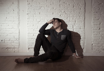 Desperate lonely unhappy caucasian man suffering from depression sitting alone on floor at home