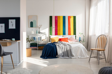 Fashionable bedroom interior with colorful headboard, king size bed, chair and workspace
