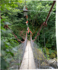 Obraz premium flashlight with colorful ribbons on the cable bridge across the river