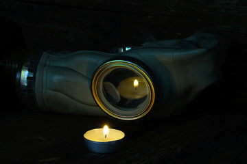 On a dark background gas mask and a burning candle. Candle fire is reflected in gas mask. The concept of a nuclear-free world