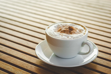 close up modern hot black coffee the cappuccino on wood background with coffee bubble foam pattern and texture in white cup looking and feel so delicious on glasses table in coffee shop.