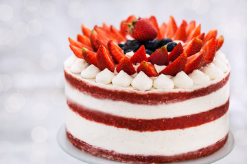 Delicious homemade naked red velvet cake decorated with cream and fresh berries