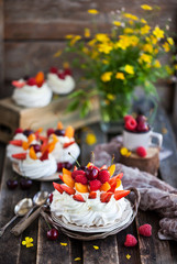 Delicious Pavlova meringue cake decorated with fresh berries on rustic background