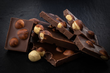 milk chocolate pieces with nuts on a dark background