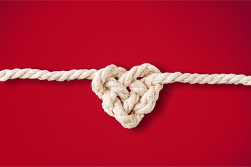 White rope in heart shape knot on background. Love concept.