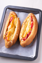Two hot dog fast food junk fresh sausage cheese sauce isolated on baking tray white background
