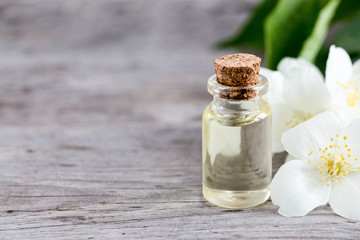 Essential jasmine oil. Massage oil with jasmine flowers on a wooden background