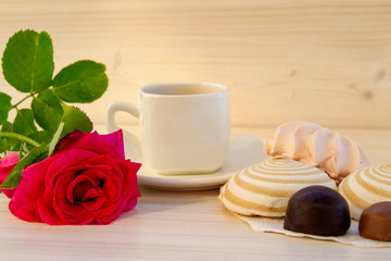 Delicate multicolored marshmallows on white openwork plate. Still life with marshmallows, a Cup of tea and a rose on vintage background.