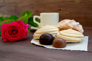 Delicate multicolored marshmallows on white openwork plate. Still life with marshmallows, a Cup of tea and a rose on vintage background.