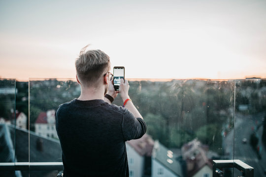 man photographing a smartphone with a view of the city from a viewing platform.