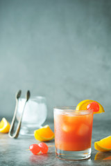 Summer cocktail. Orange juice with mint, syrop, fruit slices and cherry with ice. Dark background.