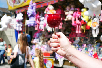 sweet candy apple on county fair or festival. red candy apple covered in red caramel, at holiday vacation event or amusement park