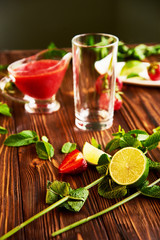 cooking of cooling summer cocktail with strawberries, ice and mint and around the berries are ripe fresh strawberries and lime