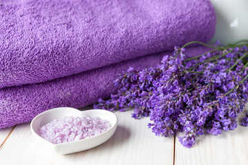 Obraz na płótnie Canvas Lavender flowers, aromatic sea salt and towels. Concept for spa, beauty and health salon, cosmetics store. Close up photo on white wooden background.