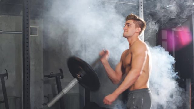 Caucasian muscular shirtless bodybuilder, flexing weight plates on iron bar. Weightlifting training.