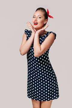 portrait of surprised pin up woman in polka dot dress. cute girl posing in retro style
