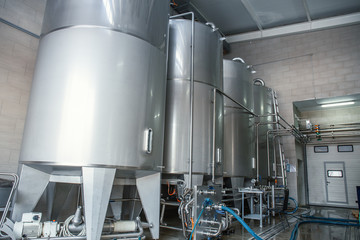 Stainless steel or metal juice factory equipment, large reservoirs or tanks and pipes in modern plat