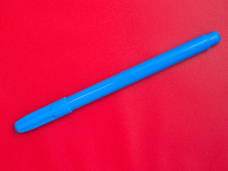 Blue marker isolated on red background, diagonal placement.