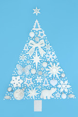 Abstract Christmas tree decoration with white and silver baubles and snowflakes on pastel blue background. Traditional theme with symbols for the festive season.