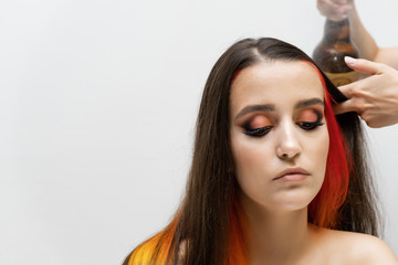 Photo portrait of the work of the master hairdresser makes a fashionable hairstyle with a hair dryer and a hairbrush in the studio on a white background. The brunette model has colored hair.