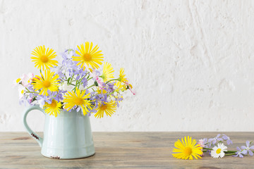 spring flowers in vintage jug on wooden table