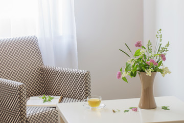 cup of tea, open book and summer  bouquet in vase indoor