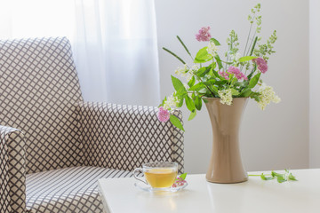 cup of tea and summer  bouquet in vase indoor