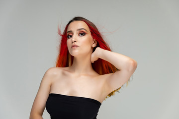 A close-up portrait photo of a fashionable hairstyle red-yellow in studio on a white background. The pretty brunette model with beautiful make-up has beautiful flowing colorful hair.