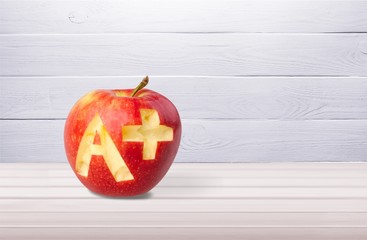 Photo of red apple with A+ on the school desk