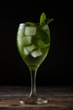 Summer cocktail or drink in wine glass. Refreshing drink with mint leaves, gin tonic, syrop. Dark photo.