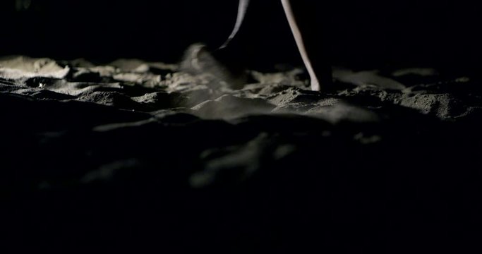 Feet, feet close-up walking on the sandy beach in the dead of night.