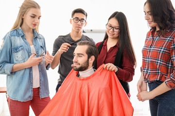 Professional hairdresser and trainees working with client in salon. Apprenticeship concept