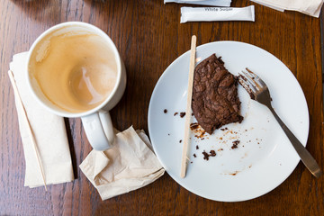 Empty glass coffee latte with latte froth in the bottom and chocolate cookies, shock half a loaf. On wooden table