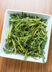 Water mimosa (Neptunia oleracea Lour.) white plate on a wooden floor.