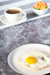 Fried eggs in white plate and coffee for breakfast on a light background on a sunny day.