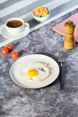 Fried eggs in white plate and coffee for breakfast on a light background on a sunny day.