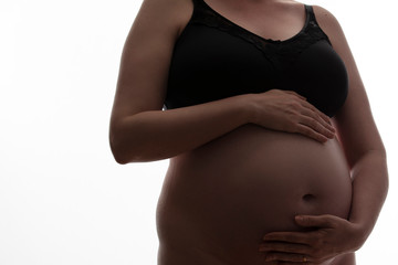 Pregnant woman with a baby bump silhouetted on a white background