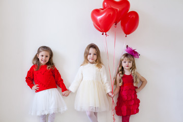 Three little beautiful girls in red hold hands