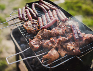 Grilling sausages on barbecue grill. Pork sausage and steak in smoke. Close-up view & Selective focus. 