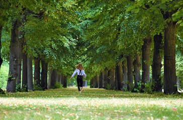 Fototapeta premium slim girl blonde runs along the trees in the park