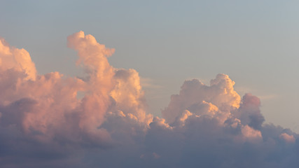 Close up view of beautiful colored cumulus fluffy clouds with pink and purple hues in the blue sky at sunset background - obrazy, fototapety, plakaty