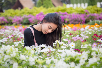 Obraz na płótnie Canvas Beautiful Asian girl in pink dress are sitting in the garden flowers at Bangkok , Thailand. Beautiful Women with flowers and nature concept.
