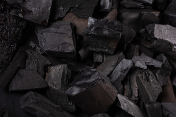 Natural fire ashes with dark grey black coals texture. It is a flammable black hard rock. Space for text.