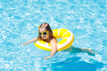 Child in swimming pool on ring toy. Kids swim.