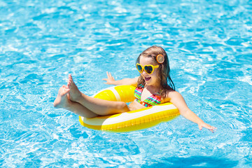 Child in swimming pool on ring toy. Kids swim.