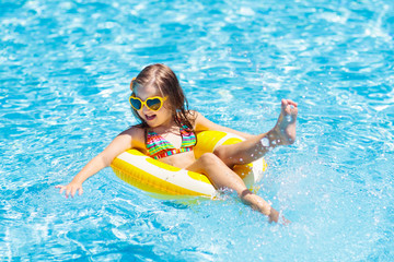 Child in swimming pool on ring toy. Kids swim.